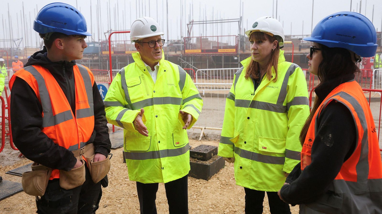 Site team in hi-vis jackets and hard hats talking on a housing construction site